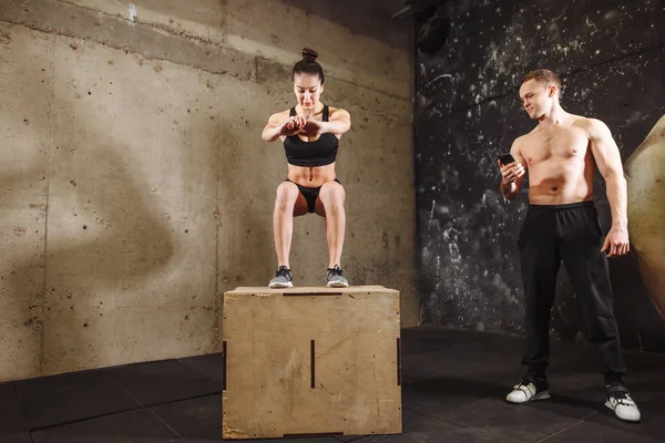 woman jumping on fit box with male trainer