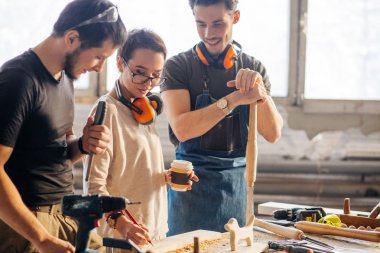 Marangoz, kadın çırağı uçağı kullanması için eğitiyor.