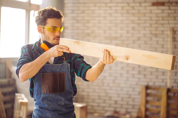Плотник тестирует равномерность деревянных досок в мастерской — стоковое фото
