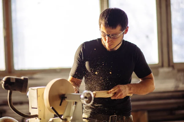 O homem que trabalha no torno de madeira pequeno, um pedaço de madeira do carves do artesão — Fotografia de Stock