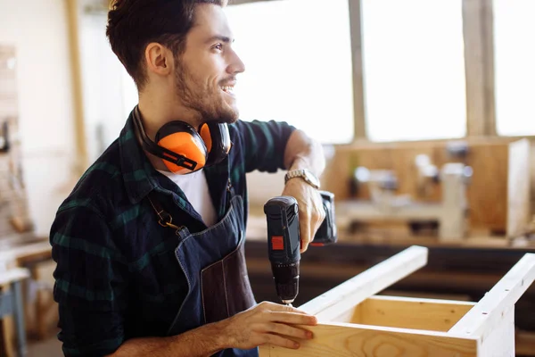 Carpenter drills a hole with an electrical drill — Stock Photo, Image