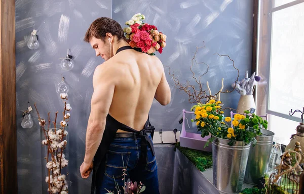 Florista nu para a cintura e colocando flores em seus ombros na loja de flores — Fotografia de Stock