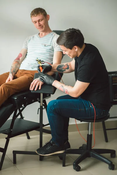 Maître tatoueur dans des gants fait tatouage — Photo