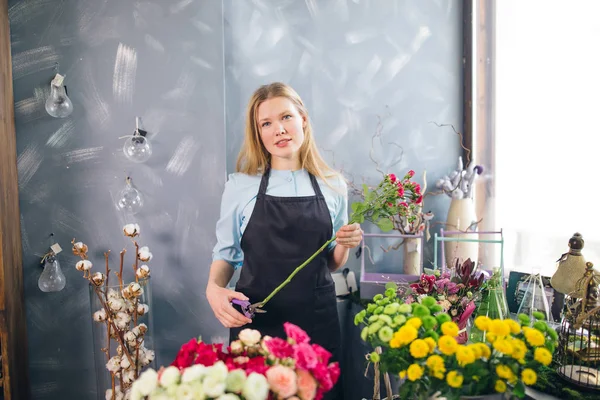 Mujer joven sosteniendo flor larga y cortando en floristería — Foto de Stock