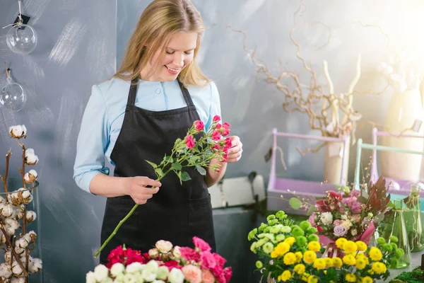 Lekfull Visa shop Assistant röra underbara blommor framför skrivbord — Stockfoto