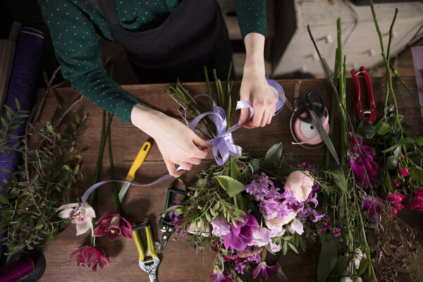 close up shot of hands tying bow on flowers at the table