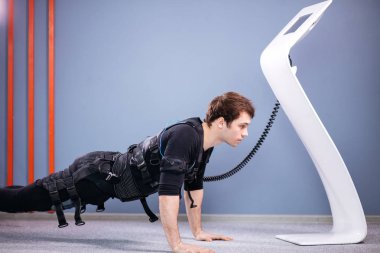 tahta egzersiz yaparak elektrik kas stimülasyonu elbiseli adam. EMS