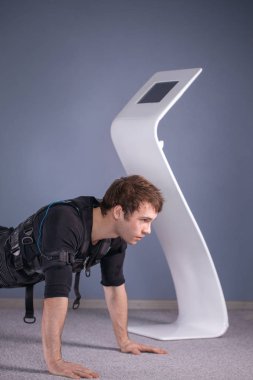 tahta egzersiz yaparak elektrik kas stimülasyonu elbiseli adam. EMS