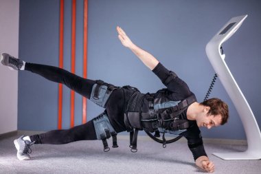 yan tahta egzersiz yaparak elektrik kas stimülasyonu elbiseli adam. EMS