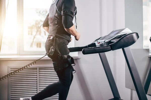Homme en costume noir pour ems entraînement en cours d'exécution sur tapis roulant à la salle de gym — Photo