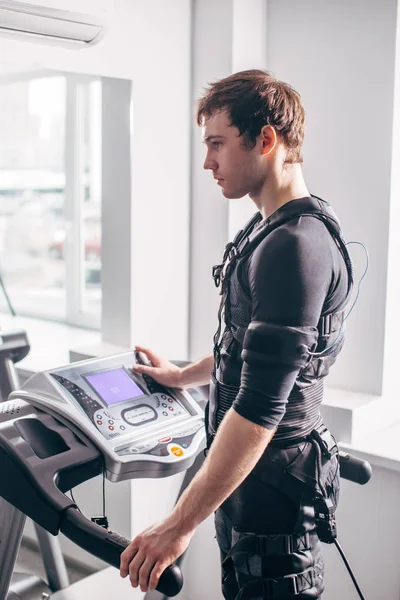 Hombre en traje negro para entrenamiento ems corriendo en la cinta de correr en el gimnasio — Foto de Stock