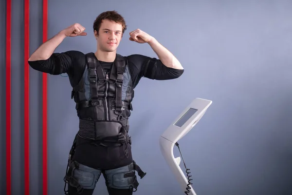 Hombre cerca de la máquina EMS, estimulación muscular, mostrando bíceps — Foto de Stock