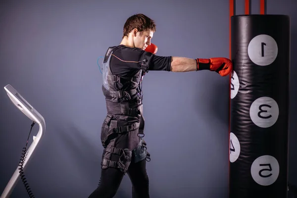 Человек в боксёрских перчатках во время тренировки. боксер в костюме электростимуляции — стоковое фото