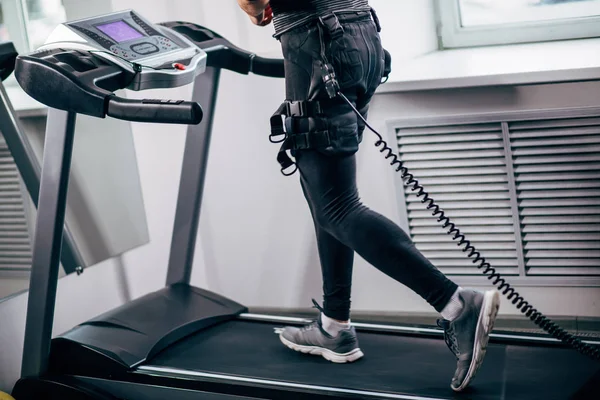 Man in electric muscle stimulation suit for ems training running on treadmill