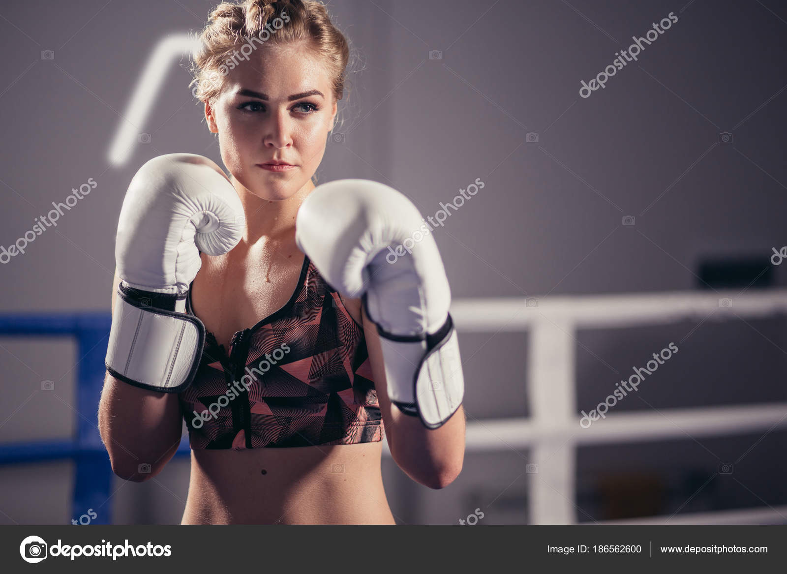 Female Boxer wearing gloves posing in boxing studio — Stock Photo © 186562600