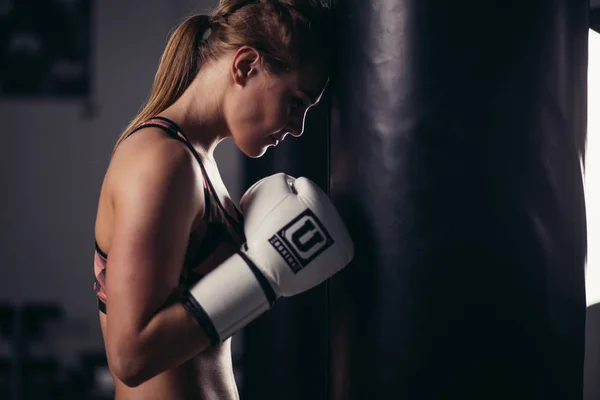 Combattante dans un gymnase avec sac de boxe. Femme cheveux longs modèle de fitness — Photo