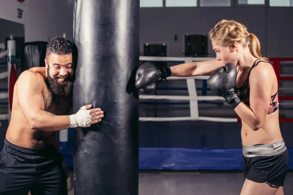 Женщина тренируется с боксерскими перчатками и боксерской грушей со своим тренером . — стоковое фото