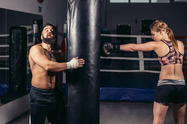Frau trainiert mit Boxhandschuhen und Boxsack mit ihrem Trainer. — Stockfoto