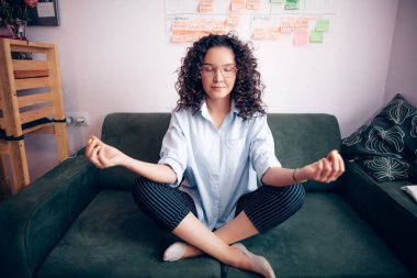 dalgalı saç ve evde kanepede yoga yaparken gözlük ile kız