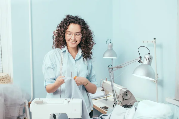 Sastrería mirando tela azul en sus brazos en el trabajo —  Fotos de Stock