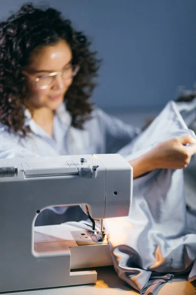 Tiro vertical de la máquina de coser moderna, modista está detrás de él . — Foto de Stock