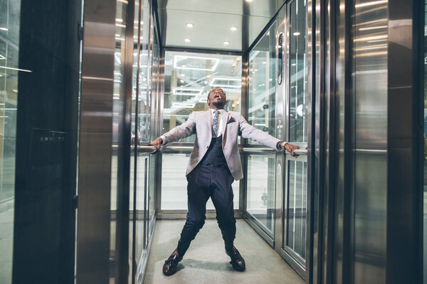 african Businessman screaming in elevator. fear claustrophobia concept