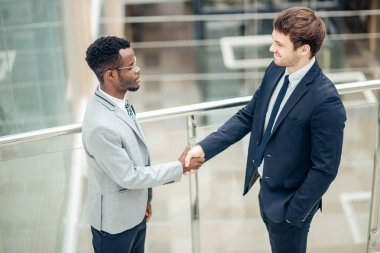 iki çok ırklı işadamları el sıkışma büyük sonu için modern ofis