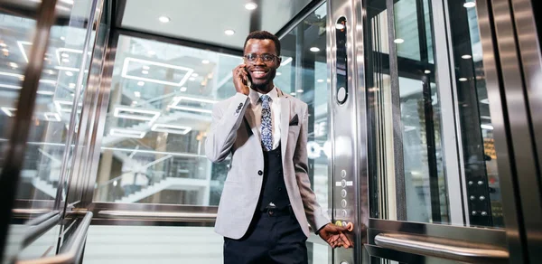 電話で話しているガラスのモダンなエレベーターの afroamerican ビジネスマン — ストック写真