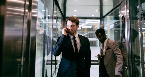 Business man standing in elevator and use smartphone