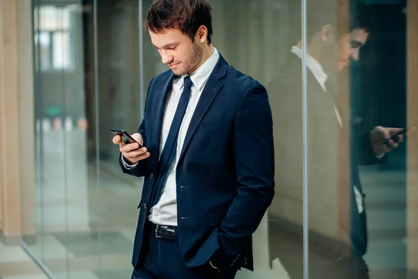 Üzletember, a smartphone, mint irodaház — Stock Fotó