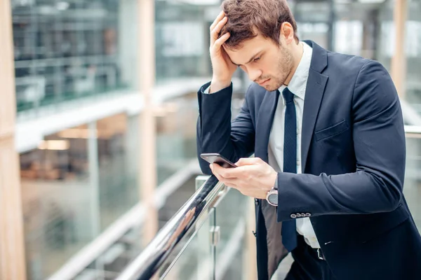 Aggódik fiatal üzletember olvasható szöveg-ra mozgatható telefon — Stock Fotó