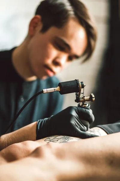 Tatuaje artista masculino hace un tatuaje en una pierna femenina . —  Fotos de Stock