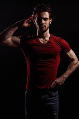 Kırmızı T-shirt ve jeans içinde yakışıklı bir genç adam Selam poz ayakta