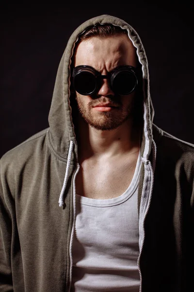 Vertikala porträtt av arg ung man klädd i grön hoodie och glasögon — Stockfoto