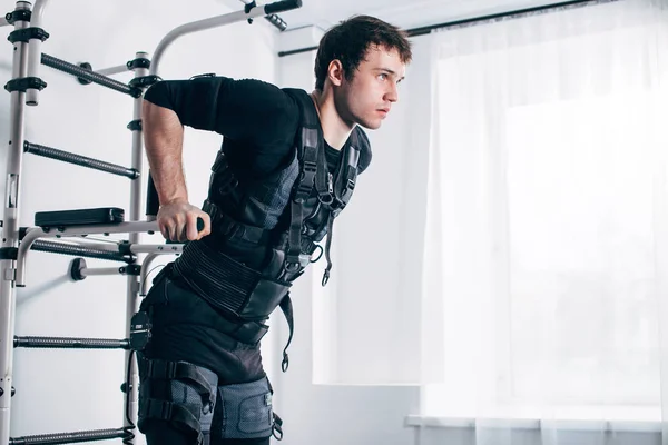 EMS masculino haciendo ejercicio, haciendo flexiones. hombre haciendo tríceps inmersiones en barras paralelas — Foto de Stock