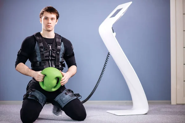 Homem em terno muscular elétrico para estimular com bola de medecina de treinamento — Fotografia de Stock