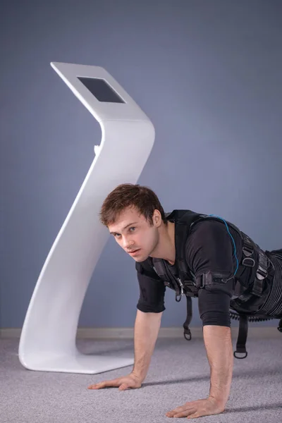 Hombre en trajes de estimulación muscular eléctrica haciendo ejercicio de tablón. EMS — Foto de Stock