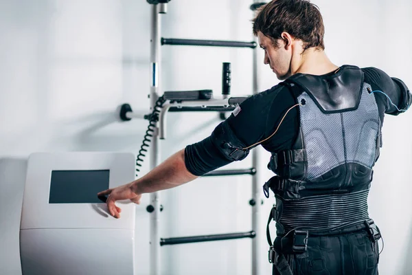 Atleta que regula la intensidad de la máquina de estimulación electro muscular ems — Foto de Stock
