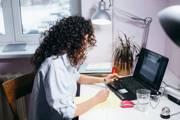 Yan görünümü atış genç kadının işyerinde oturan ve laptop ile çalışma — Stok fotoğraf