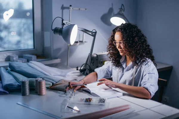 Meisje met serieuze blik lezen van notities van notebook in avond op werkplek — Stockfoto