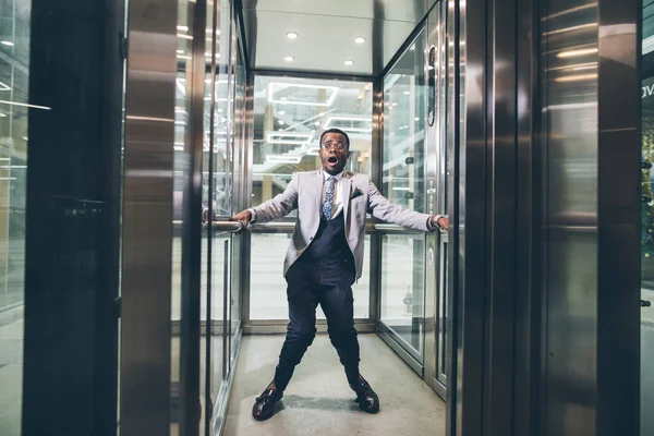 エレベーターの中悲鳴しているアフリカの実業家。恐怖閉所恐怖症の概念 — ストック写真