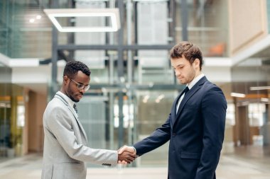 iki çok ırklı işadamları el sıkışma büyük sonu için modern ofis