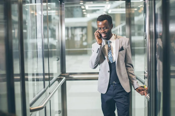 電話で話しているガラスのモダンなエレベーターの afroamerican ビジネスマン — ストック写真
