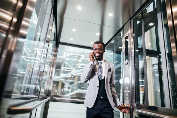 電話で話しているガラスのモダンなエレベーターの afroamerican ビジネスマン — ストック写真