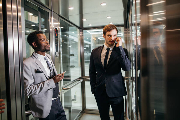 Business man standing in elevator and use smartphone