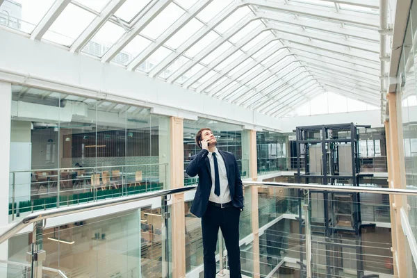 Business man walking while talking on mobile phone on his way to work