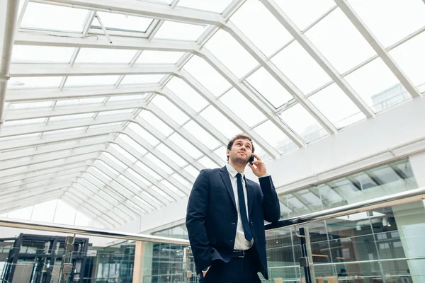 Business man walking while talking on mobile phone on his way to work