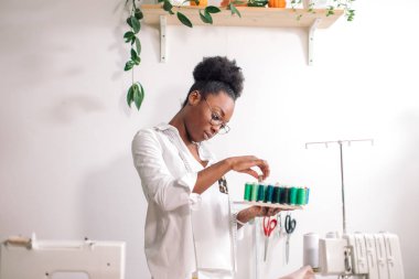 Afrikalı terzi kadın ipliklerle bobinler tutuyor.