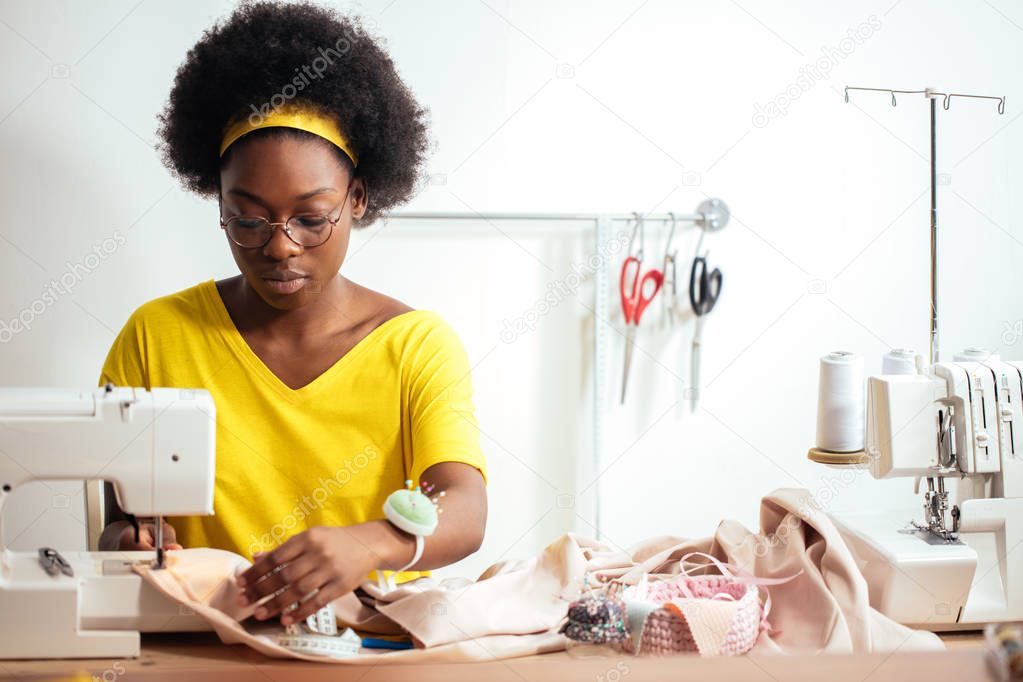 woman seamstress sitting and sews on sewing machine. Dressmaker working