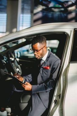 Bir tablet tutan galeride ayakta yakışıklı Afrika araba satıcısı